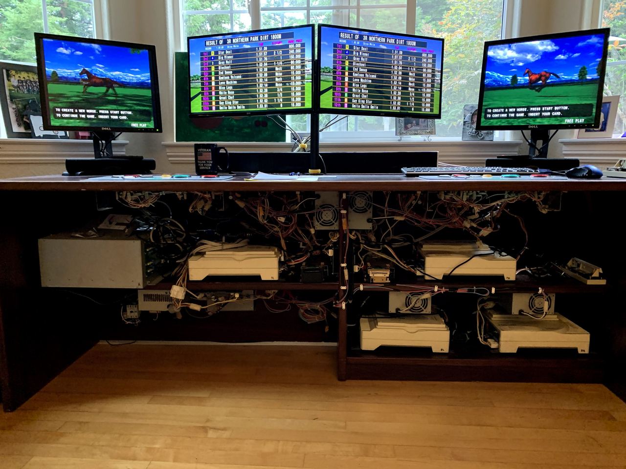 Four monitors running Derby Owners Club above a rack of linked Sega NAOMI arcade boards.