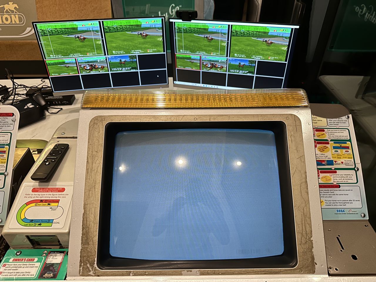 An original arcade CRT monitor beside a Derby Owners Club control panel and horse cards.