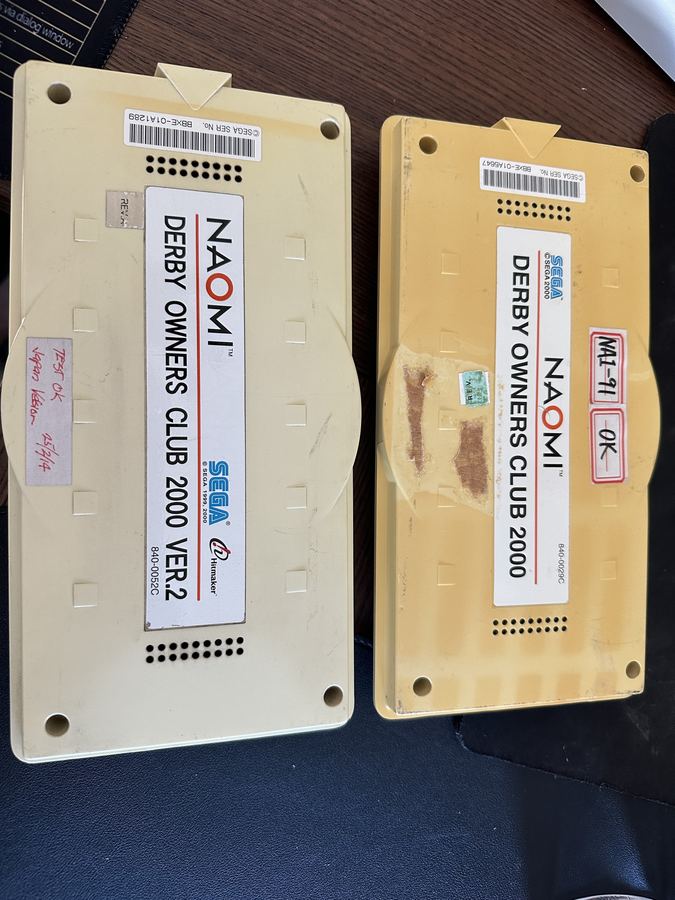 Two Sega NAOMI cartridges labelled Derby Owners Club 2000 and Derby Owners Club 2000 Ver.2.